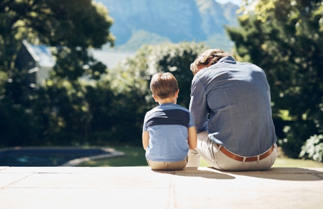 father and son sitting outside while talking